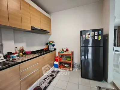 Modern kitchen with wooden cabinets and black refrigerator, featuring a cozy open layout.