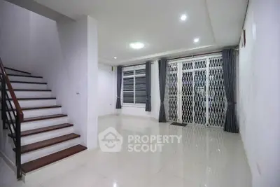 Spacious modern living room with sleek staircase and large windows for natural light.