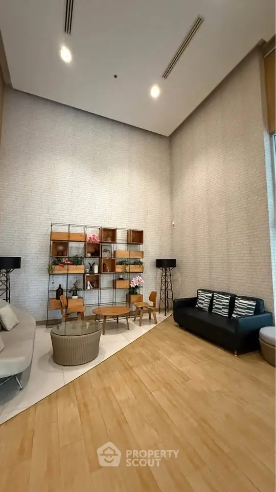 Modern lobby with stylish seating and decorative shelving in a high-ceilinged space.