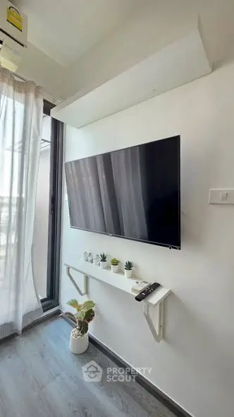 Modern living room with wall-mounted TV and balcony access