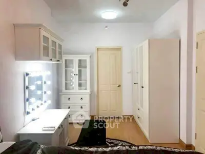 Spacious bedroom with elegant white furniture and vanity mirror lighting.