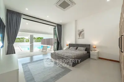 Luxurious bedroom with pool view and modern decor in a spacious open layout.