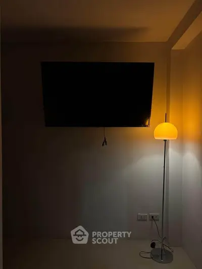 Minimalist living room with wall-mounted TV and modern floor lamp.