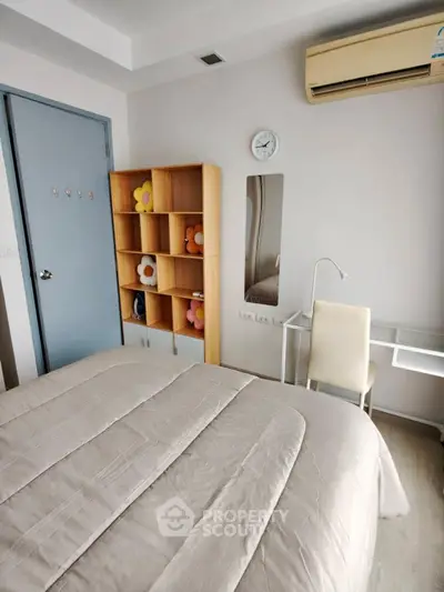 Cozy bedroom with modern decor and air conditioning, featuring a stylish shelving unit and comfortable bedding.