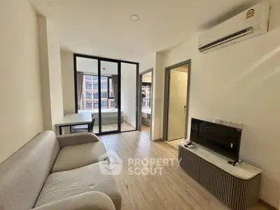 Modern living room with sleek design and natural light, featuring a cozy sofa and air conditioning.
