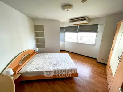 Spacious bedroom with wooden flooring and large windows in modern apartment