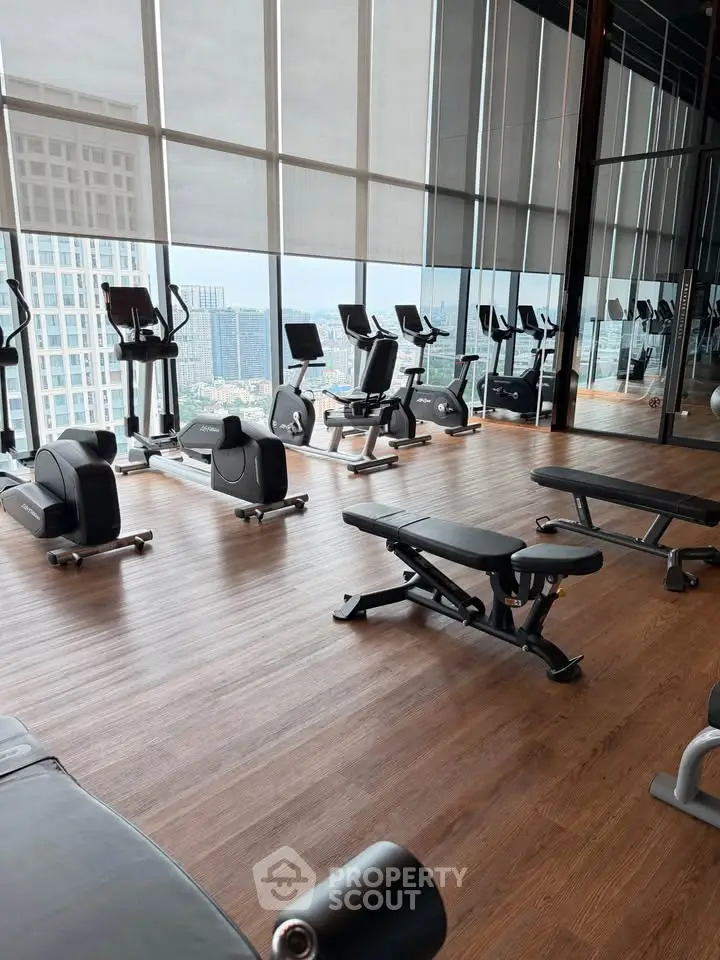 Modern gym with city view, featuring state-of-the-art exercise equipment and floor-to-ceiling windows.