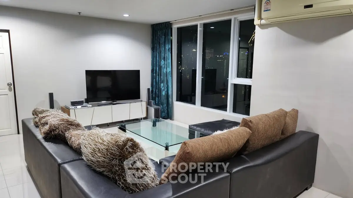 Modern living room with city view, featuring sleek furniture and large windows for natural light.