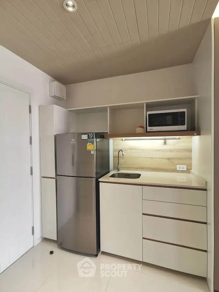 Modern compact kitchen with sleek cabinetry and stainless steel fridge