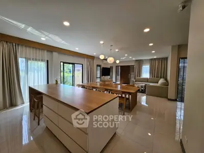 Spacious modern living room with open kitchen and large windows for natural light.