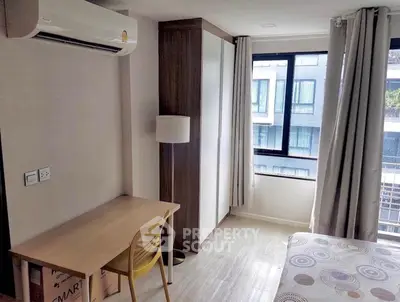 Modern bedroom with study area, large window, and air conditioning in a stylish apartment.