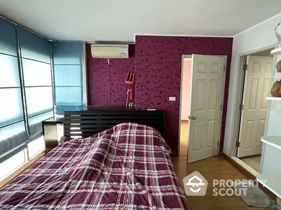 Spacious bedroom with a striking purple feature wall, large windows allowing ample natural light, and modern furnishings, perfect for relaxation and comfort.