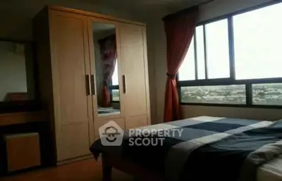 Cozy bedroom with large window and wooden wardrobe, offering a serene view.