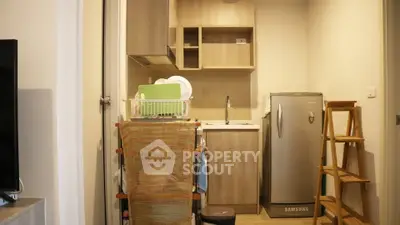 Compact kitchen with modern appliances and wooden cabinetry in cozy apartment