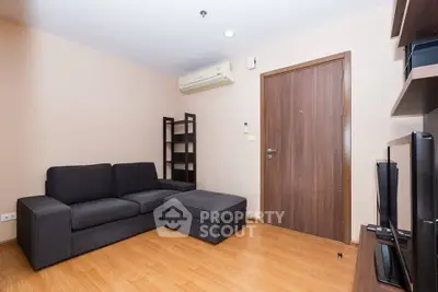 Modern living room with sleek black sofa and wooden flooring, perfect for cozy relaxation.