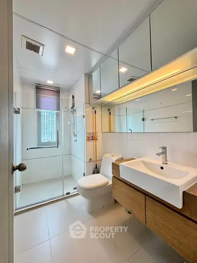 Modern bathroom with sleek fixtures and glass shower enclosure in a contemporary apartment.