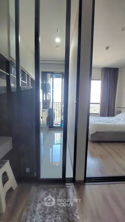 Modern apartment interior with bedroom and balcony view, featuring sleek design and natural light.