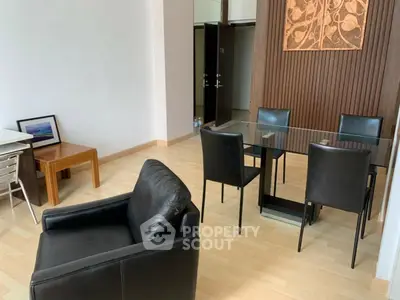 Modern dining area with glass table and leather chairs in a stylish apartment.