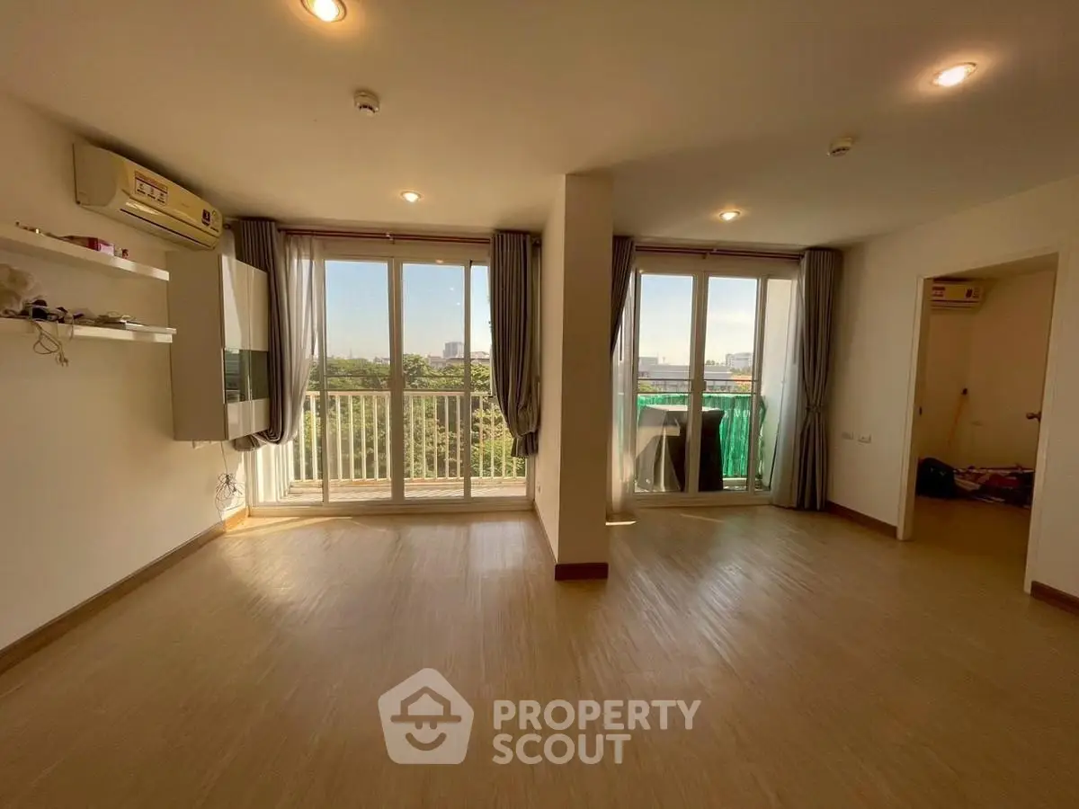 Spacious living room with large windows and balcony access, offering abundant natural light and scenic views.