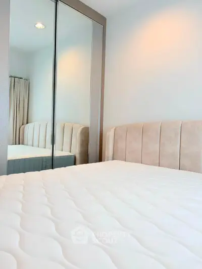 Modern bedroom with mirrored closet and plush headboard in a stylish apartment.