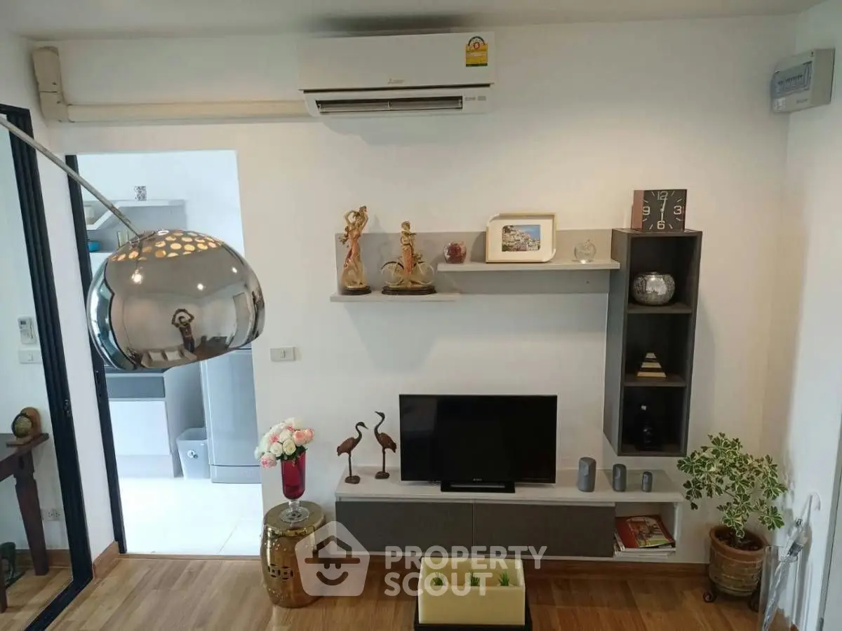 Stylish living room with modern decor and air conditioning, featuring elegant shelving and a cozy TV setup.