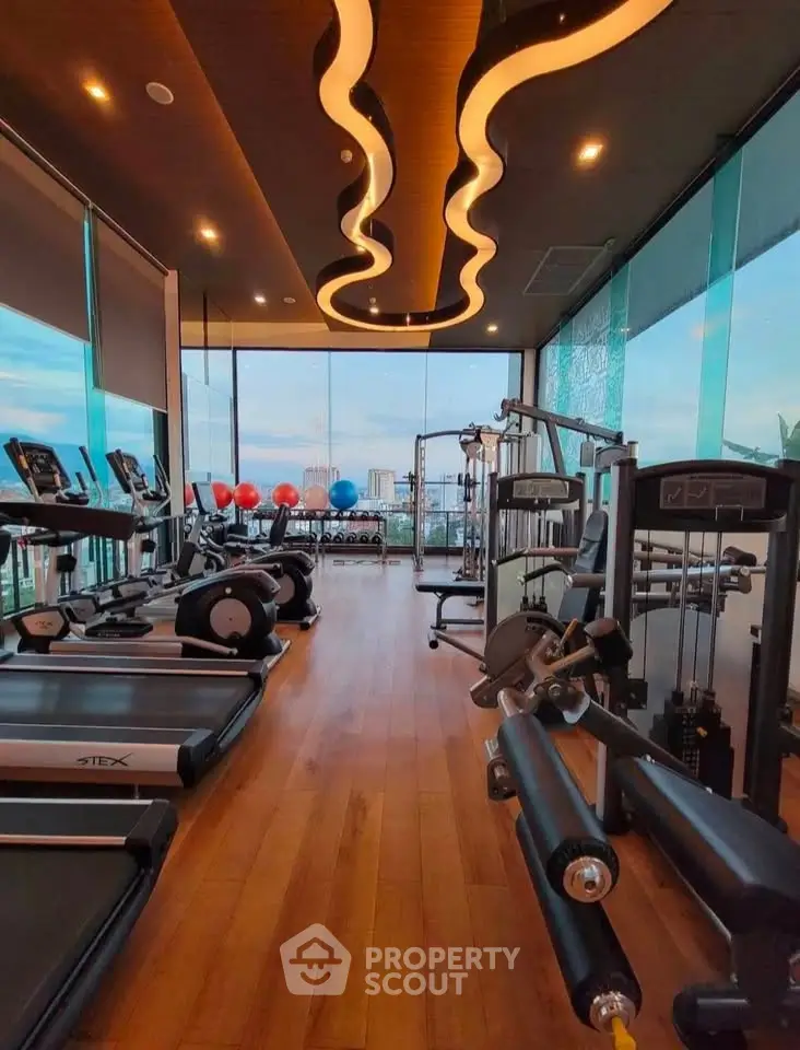 Luxurious high-rise gym with panoramic city views and modern equipment.