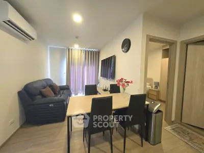 Modern living room with sleek furniture and wall-mounted TV in a cozy apartment setting.