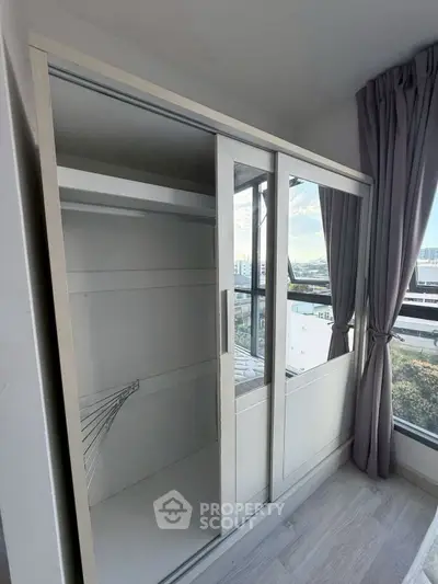 Spacious bedroom with large mirrored wardrobe and scenic window view