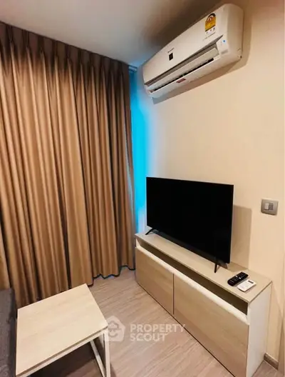 Cozy living room with modern air conditioning and sleek TV setup, perfect for relaxation.