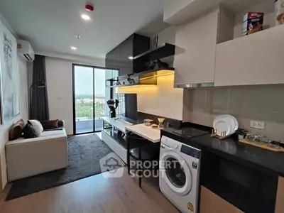 Modern living room with open kitchen and washing machine, featuring a balcony with a view.