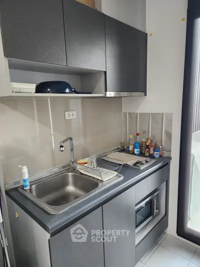 Modern compact kitchen with sleek cabinetry and stainless steel sink, perfect for urban living.