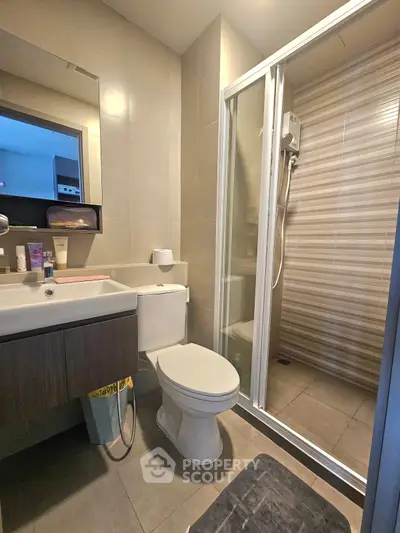 Modern bathroom with shower enclosure and sleek vanity in contemporary apartment.