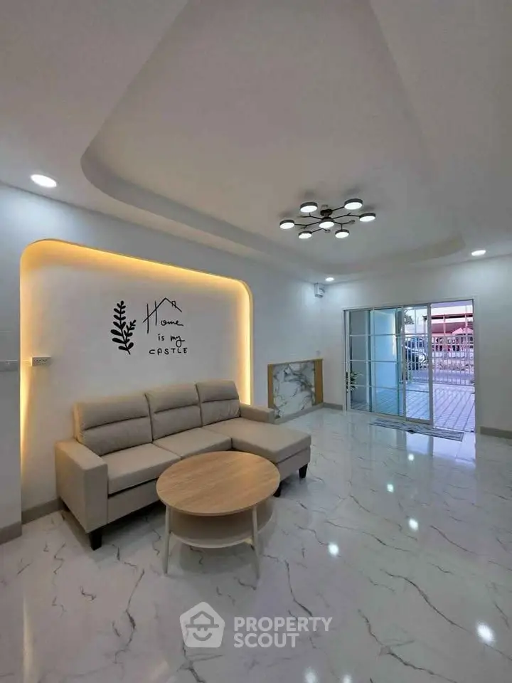 Spacious modern living room with elegant lighting and marble flooring, featuring a cozy sofa and stylish decor.