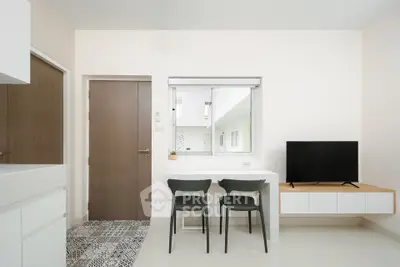 Modern minimalist interior with TV, chairs, and sleek cabinetry in a bright, open space.