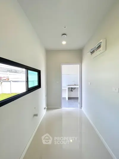 Bright hallway leading to a modern kitchen with sleek design and ample natural light.