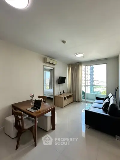 Modern living room with balcony view in a high-rise apartment, featuring sleek furniture and natural light.
