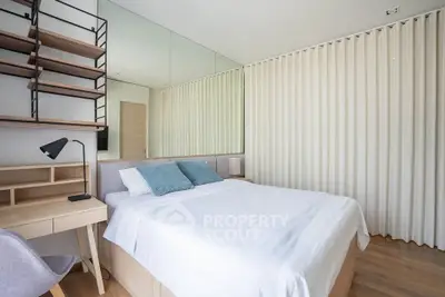 Modern bedroom with stylish decor and ample natural light, featuring a cozy bed and functional workspace.