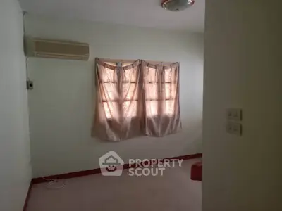 Cozy bedroom with air conditioning and natural light through curtained windows.
