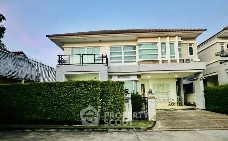 Modern two-story house with lush green hedge and spacious driveway