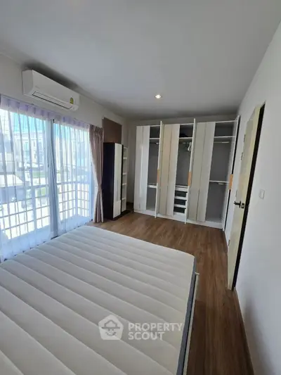 Spacious bedroom with large windows and built-in wardrobe in modern apartment