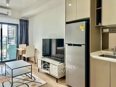 Modern living room with balcony, sleek furniture, and stainless steel appliances.