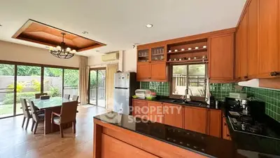 Spacious kitchen with wooden cabinets and garden view, featuring open layout and dining area.
