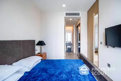 Modern bedroom with blue bedding and wall-mounted TV in luxury apartment