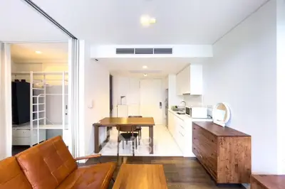 Modern open-plan living room with stylish furniture and compact kitchen area.