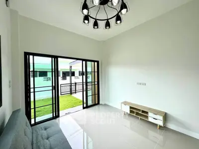 Modern living room with stylish chandelier and access to a green balcony, featuring sleek tile flooring and minimalist decor.