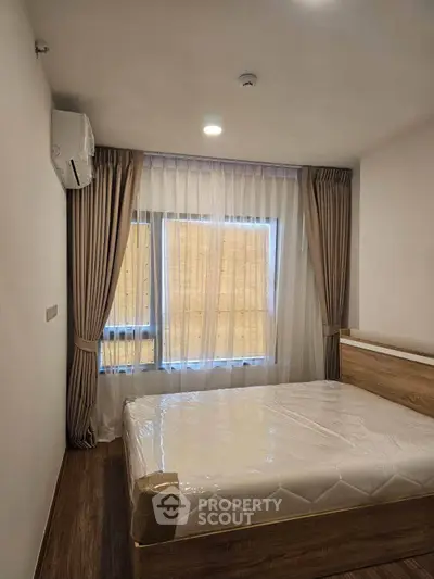 Modern bedroom with natural light, featuring a cozy bed and elegant curtains, perfect for relaxation.