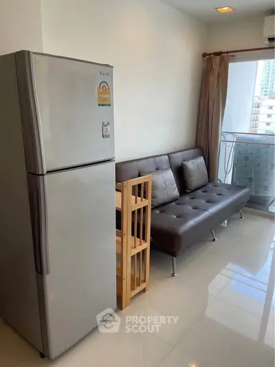 Modern apartment with sleek fridge and cozy seating area near balcony.