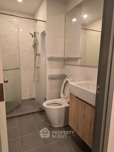 Modern bathroom with glass shower and sleek fixtures in contemporary apartment.