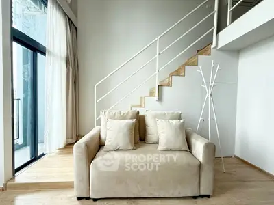 Modern living room with stylish staircase and cozy beige sofa, perfect for urban living.
