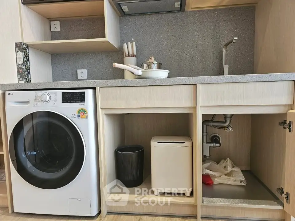 Modern kitchen with washing machine and sleek cabinetry, perfect for efficient living.